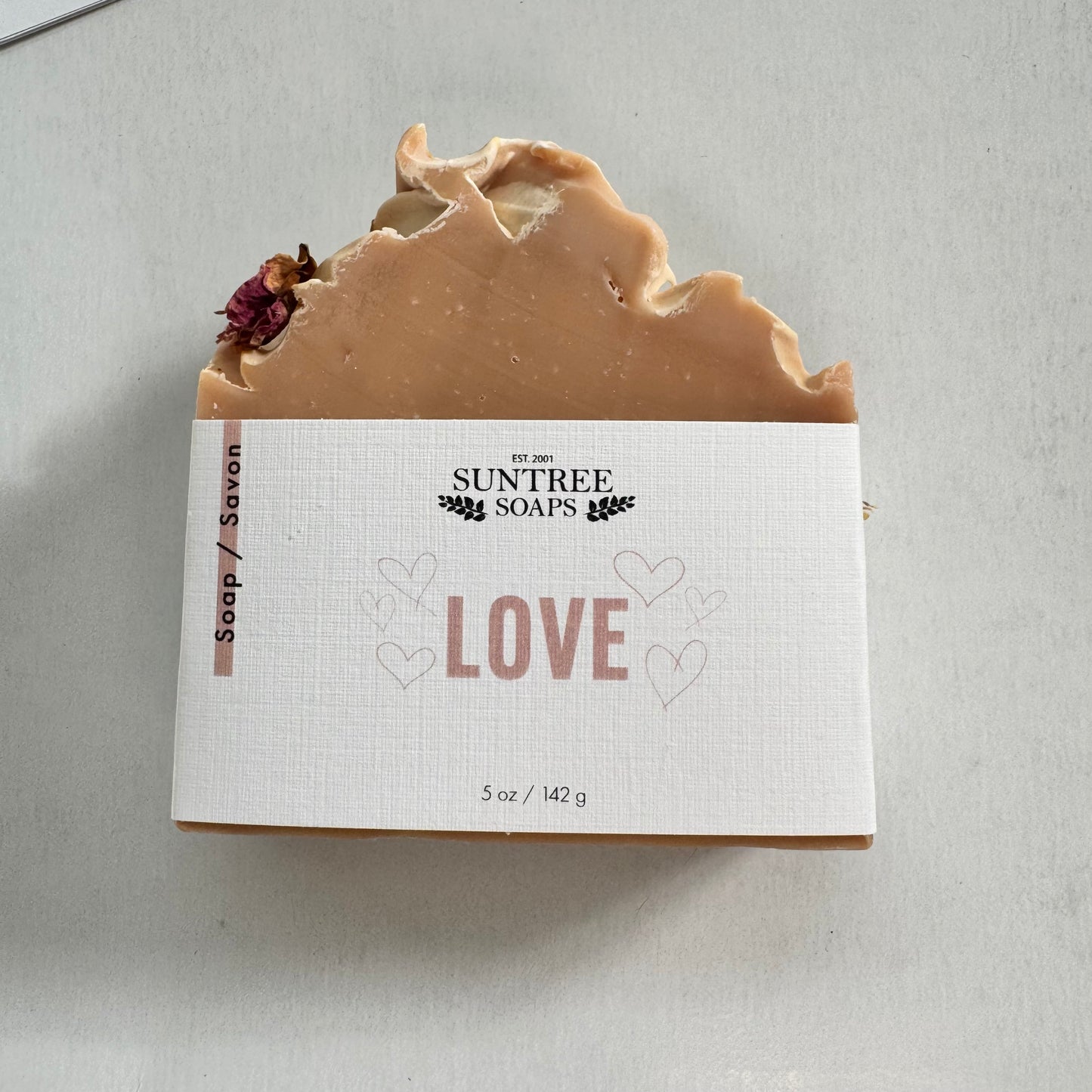 Natural soap bars by Suntree Soaps displayed in a rustic setting with varied colors and textures.