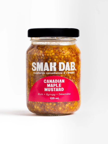 Smak Dab gourmet mustard jar with a rich, golden-yellow texture, placed on a wooden surface with mustard seeds nearby.